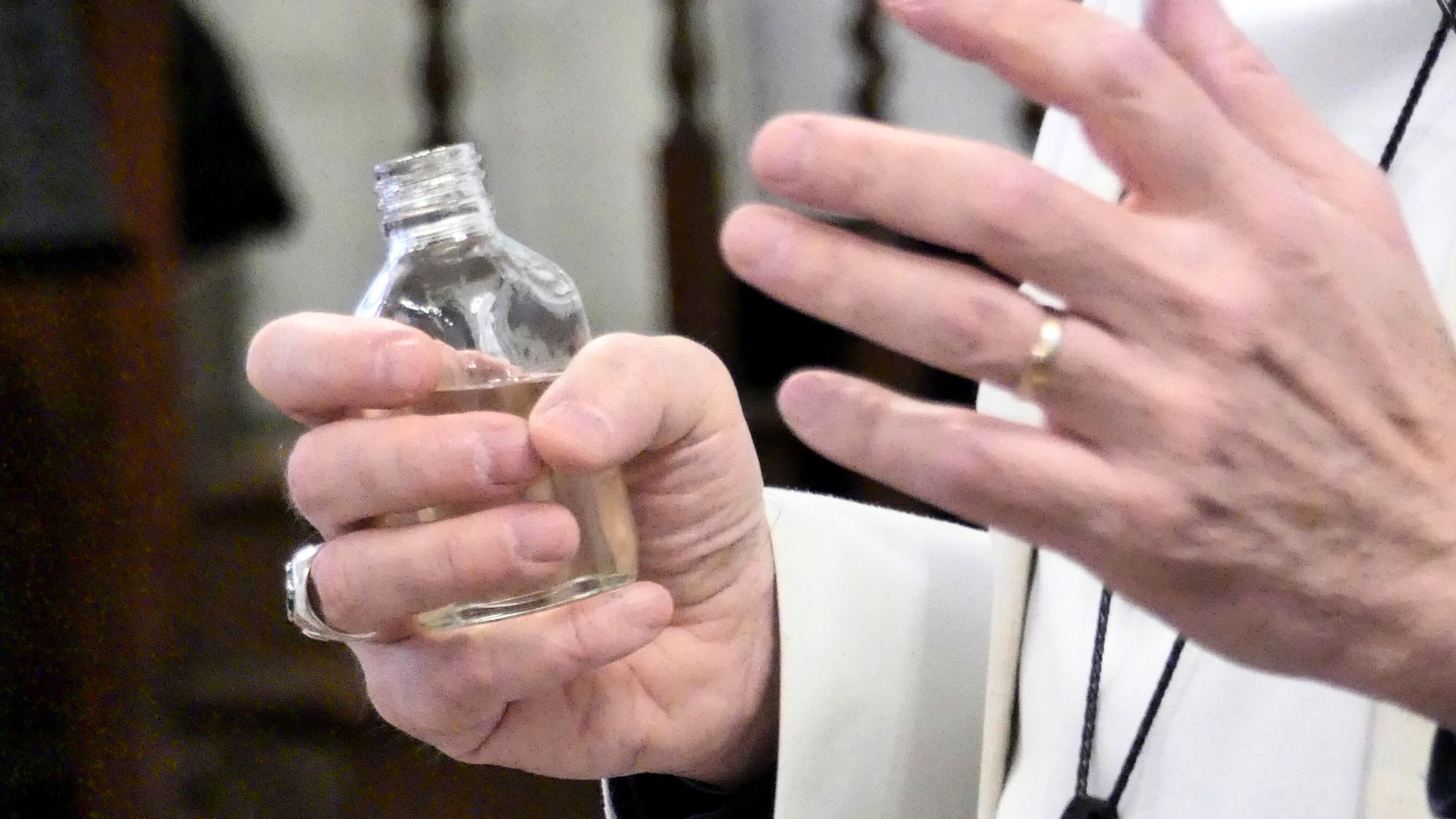 Bishop Simon holds the glass bottle of oil in his hands