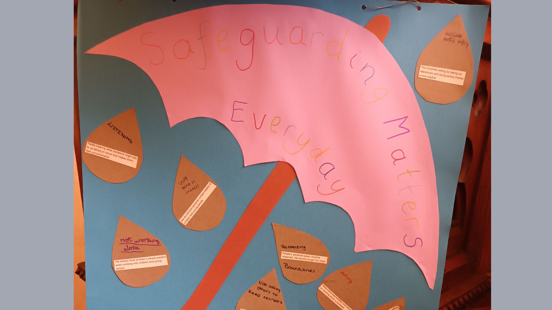 A display with a pink paper umbrella says,’Safeuarding matters everyday’