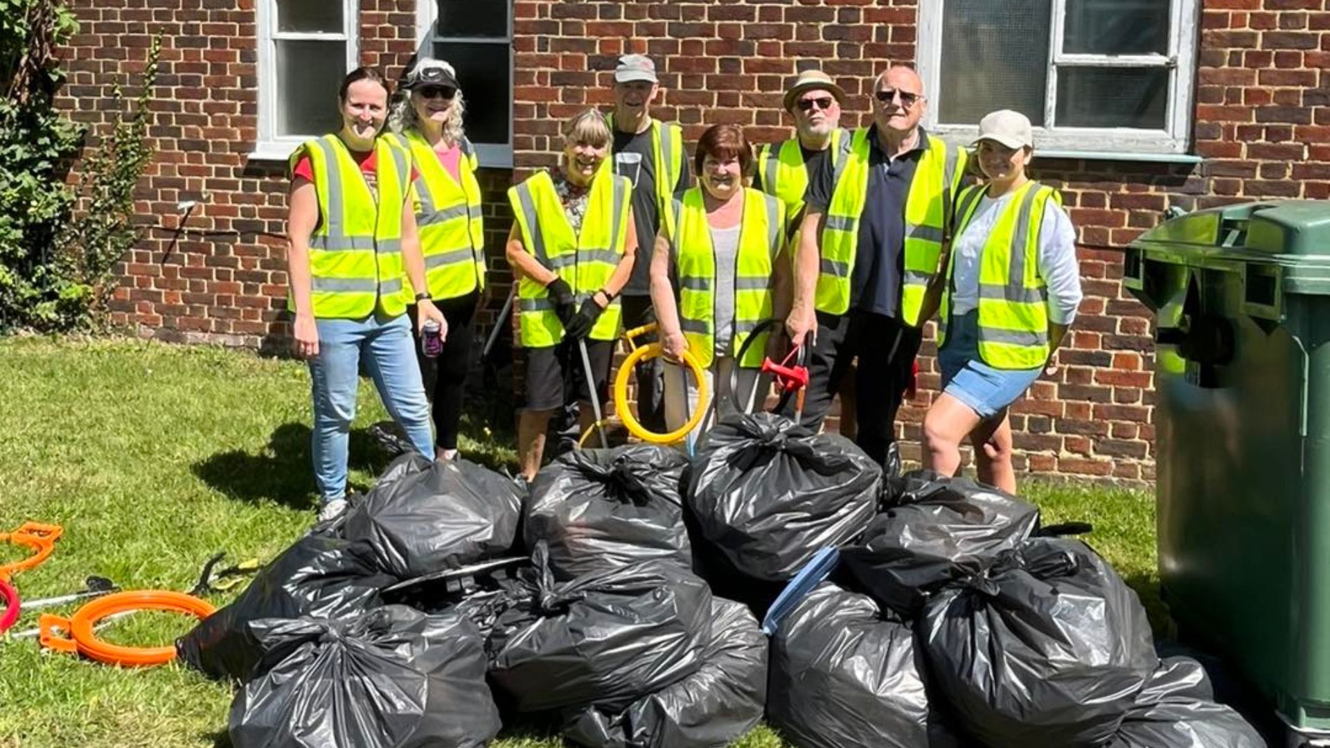 Litter pickers in high vis jackest stand behind bags of full bin liners