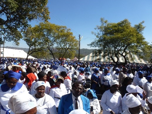 A large group of worshippers gather outside to attend a worship event in Zimbabwe