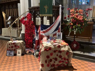 The shape of a saluting soldier made out of poppies, the Union flag and a collection of war memorabilia, adorn a table draped with poppies inside the church.